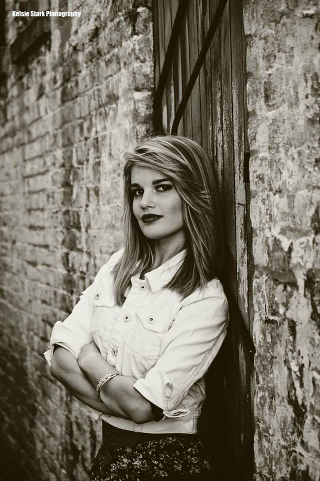 Black and white photo of girl leaning against door